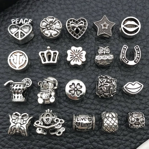 Macro shot of silver alloy charm beads featuring heart, crown, and star on black leather