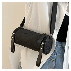 Close-up of black barrel shoulder bag with 3D bubble texture and wide woven strap