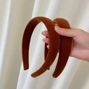 Detail of two wide padded velvet headbands in caramel brown with retro plush texture