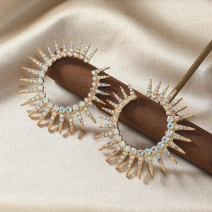 Macro detail of sunburst floral earrings with multi-color crystals on champagne silk