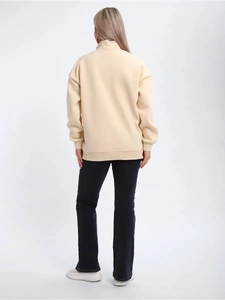 Rear view of a beige half-zip sweatshirt showing the standing collar and ribbed cuffs