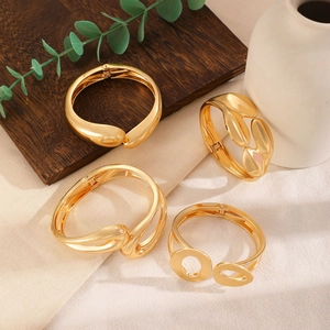 Detail view of a 4-piece set of chunky gold-tone irregular alloy bangles on linen cloth