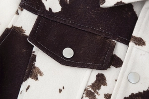 Macro detail of cow print jacket showing soft flannel texture and silver snap button