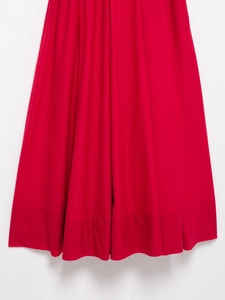 Detail of red poplin maxi dress hemline featuring pleated fabric and high-quality stitching