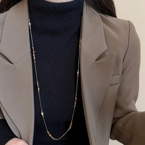 Detail of tiger eye beaded necklace worn on a black sweater for a vintage look
