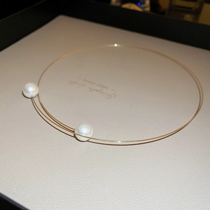 Detail of minimalist gold choker with pearls in a beige velvet jewelry box