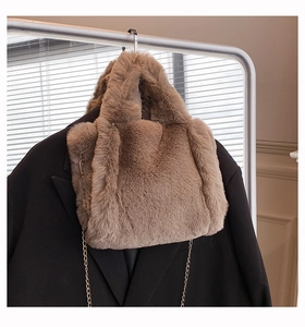 Sac cabas en fausse fourrure marron avec chaîne dorée suspendu sur un portant avec blazer