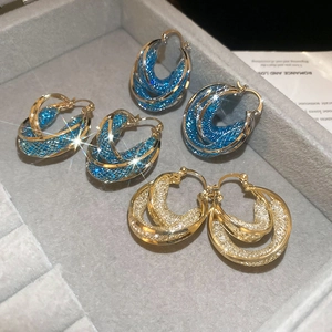 Detailed macro shot of vintage gold and blue mesh double-layer hoop earrings in a jewelry box