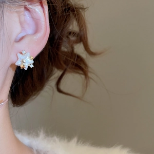 Détail d'une boucle d'oreille étoile plaquée or 14 carats avec perle et zircon sur mannequin