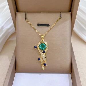 Gold snake pendant necklace with emerald green stone on a brown velvet jewelry box