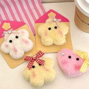 Detail of plush star and heart hair clips in soft pastel colors on a display card