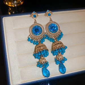 Macro view of vintage gold earrings with blue gemstones and hanging tassel beads