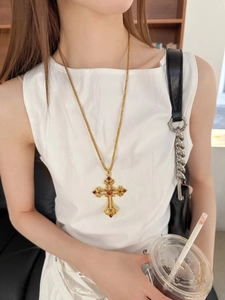 Gros plan d'un collier croix baroque vintage avec rubis et cristaux sur chaîne dorée