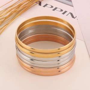 Detailed stack of seven gold, silver, and rose gold polished stainless steel bangles