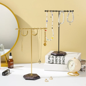 Dual T-shaped jewelry stands with marble bases for earrings and necklaces on a vanity