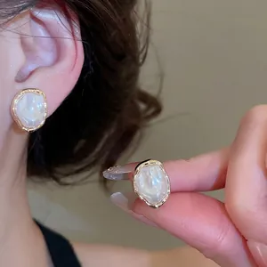 French vintage irregular pearl ear clips with gold plating shown on ear and hand