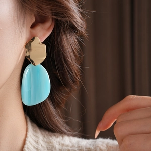 Vue détaillée de boucles d'oreilles en acrylique bleu irrégulier avec sommet doré