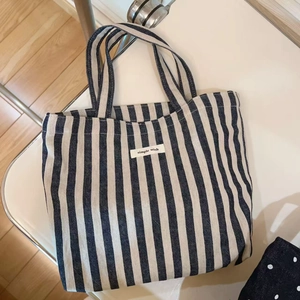 Detail of navy striped canvas tote bag featuring a stitched 'simple wish' textile label