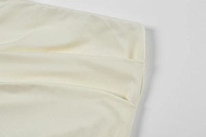 Detailed macro view of the layered ruched fabric texture on a cream lace dress