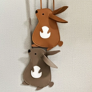 Detail view of rabbit-shaped crossbody bags in brown and grey with soft lychee texture