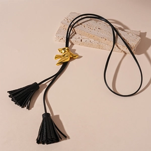 Macro detail of bird bolo tie necklace with golden metallic bird and leather tassels