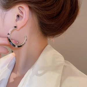 Detail of C-shaped resin tortoiseshell earrings with polished gold metal edges for women