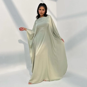 Full view of light green satin maxi dress with batwing sleeves on model in minimalist setting
