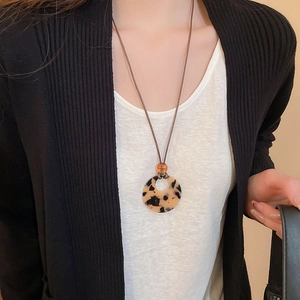 Close-up of a leopard print resin circular pendant on a brown wax cord necklace