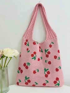 Detailed view of pink knitted tote bag with cherry pattern and handmade woven texture