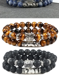 Detail of tiger eye and lava stone beaded bracelets with silver owl and Buddha charms