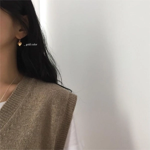 Close-up of a model wearing minimalist gold heart drop earrings with hook design