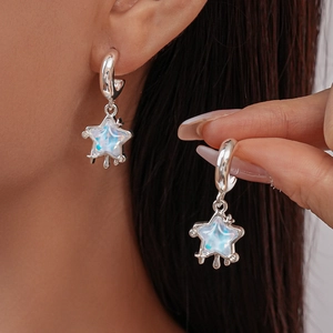Close-up of star-shaped silver drop earrings with iridescent opal stones on ear
