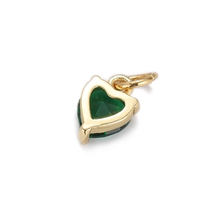 Macro detail of a gold-plated heart pendant featuring a vibrant green zircon stone