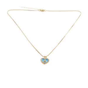 Detail of gold-plated necklace with a blue heart pendant featuring a smiley face pattern