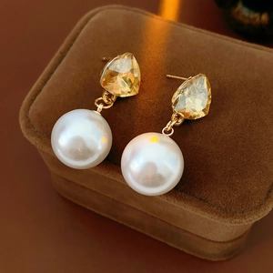 Detail of luxury triangle pearl earrings with amber gemstone on a jewelry box