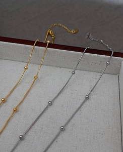 Macro shot of gold and silver snake bone necklaces with beads in a white jewelry box