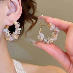Detail of natural stone pearl hoop earring with gold wire wrapping on model's ear