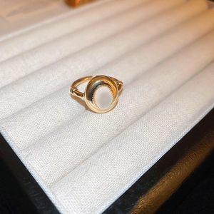 Close-up of a gold-plated dragon ring with white oval stone in a jewelry box display