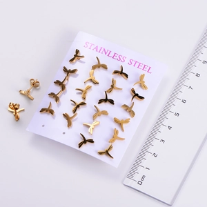 Macro shot showing small golden dragonfly stud earrings with a ruler for size reference