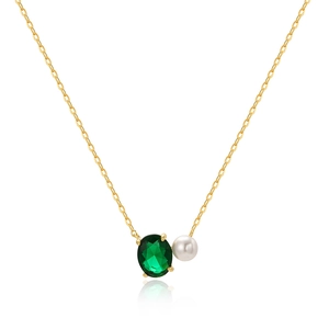 Detailed shot of golden chain necklace with emerald oval gemstone and white pearl pendant