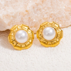 Classic 18K gold plated pearl stud earrings with gear-style edges on stone background