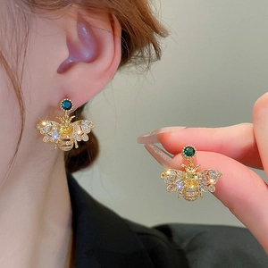 Elegant gold bee earrings with sparkling zircons and colorful crystals on woman's ear