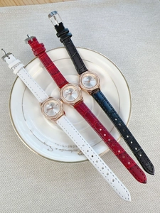 Detailed view of three quartz watches with diamond bezels and leather straps in a tray