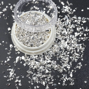 Macro shot of irregular silver metallic flakes for nail art and DIY crafts in clear jar