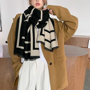 Thick geometric black and beige scarf with fringe, worn over a camel blazer for winter