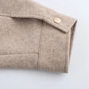 Detail of beige wool bomber jacket cuff with a polished gold metallic button accent