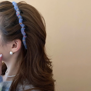 Close-up of blue tweed headband paired with elegant pearl earrings and necklace