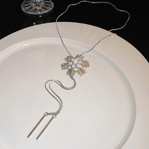 Detailed macro view of silver snowflake earrings with pearls and rhinestone tassels