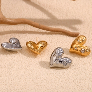Textured 18K gold and silver heart earrings with star zircon stones on natural wood