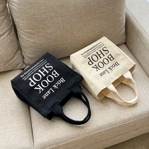 Canvas tote bags in black and white with Brick Lane Bookshop print on a sofa